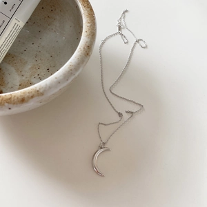 Detailed macro shot of silver moon pendant necklace with minimalist ceramic decor