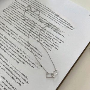 Minimalist 925 sterling silver interlocking rectangle pendant necklace on a book background