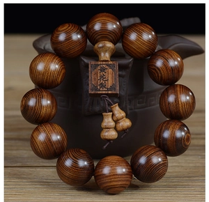 Détail de perles de prière en bois Huanghuali posées sur une théière en céramique