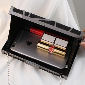 Elegant black glitter evening clutch bag with silver chain strap on white silk background
