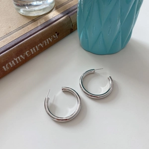 Macro detail of chunky S925 sterling silver hoop earrings with a polished metallic finish
