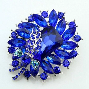 Close-up of blue gemstone floral brooch with rhinestones on a polished silver base