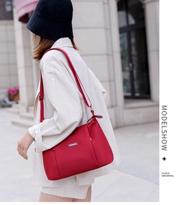 Close-up of red nylon crossbody bag featuring an adjustable strap on a female model