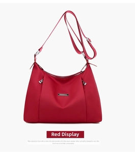 Detail of red waterproof nylon crossbody bag featuring silver zippers and adjustable strap