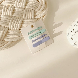 Detail of 4-piece set featuring light green and purple wavy hair clips on a card
