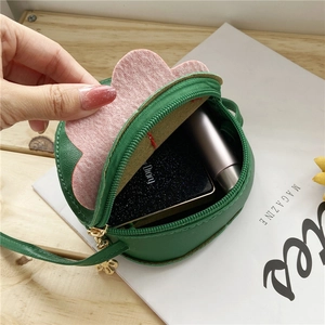 Detail view of small green cartoon strawberry bag showing interior space for small items