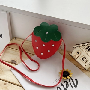 Detail of red strawberry bag featuring green leaves and silver stud accents
