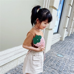 Pink strawberry crossbody bag for girls shown on model in a high-quality outdoor street setting