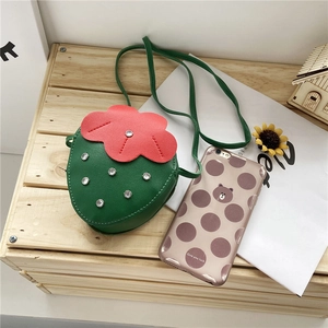 Detail shot of strawberry-shaped crossbody bag with green PU leather and sparkly rhinestones