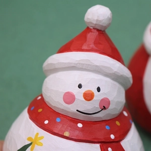Close-up of a Christmas snowman ornament with carved wood texture and red winter accessories