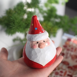 Close-up of hand-carved wooden Santa Claus figurine with red dotted hat and rustic texture