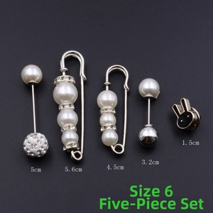 Détail du lot de 5 broches avec perles et strass sur fond à texture sombre