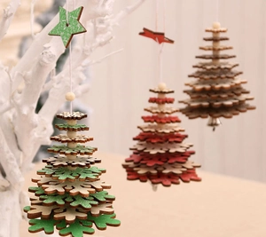 Detailed view of layered wooden Christmas tree ornaments with beads and bells on white branches