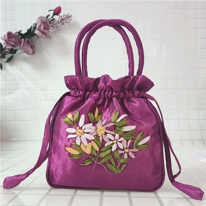 Close-up of purple satin drawstring bag with elegant floral ribbon embroidery and handle