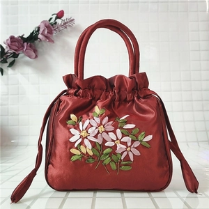 Detailed close-up of red satin bucket bag with intricate floral embroidery and drawstring