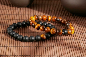 Detailed macro of tiger eye and black onyx beaded bracelets on a natural bamboo mat