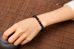 Close-up of matte black agate bracelet with yellow tiger eye stone on wrist