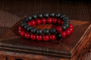 Detail of beaded couple bracelets with matte black agate and textured red volcanic stone