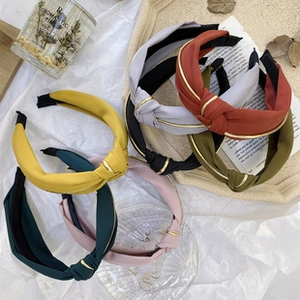 Close-up of knot headbands in seven colors with metallic edges on a wooden tray