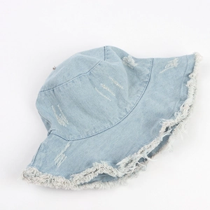 Detail of light blue denim bucket hat with distressed holes and raw frayed edge texture
