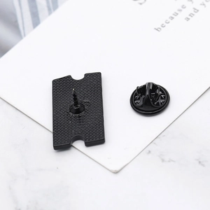 Detail view of the black alloy ticket pin back with needle and butterfly clutch