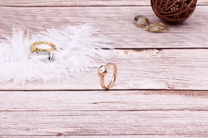 Détail macro de bagues en cœur avec diamants en or et argent sur fond de bois naturel