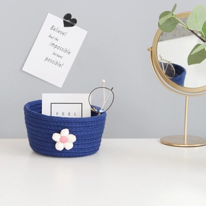 Detail of blue cotton rope woven storage basket with a decorative white fabric flower