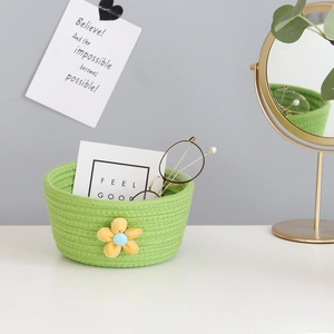 Detail view of woven cotton rope storage basket in grass green with a yellow flower