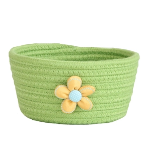 Detail of green cotton rope woven basket featuring a cute blue and yellow fabric flower