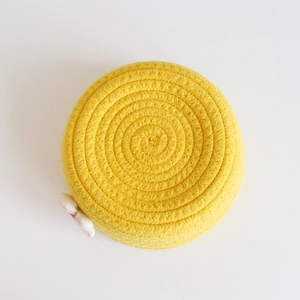 Detailed close-up of yellow woven rope storage bin lid with white floral accent