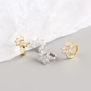 Macro shot of silver and gold marquise cut zircon flower hoop earrings on white paper
