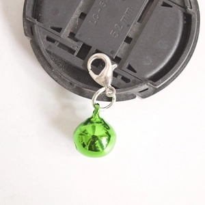 Macro shot of a vibrant green metal bell with a silver lobster clasp attachment