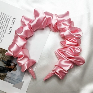 Dettaglio del cerchietto in raso rosa plissettato con finitura lucida effetto seta