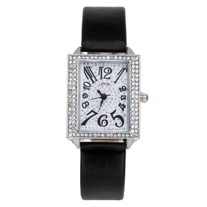Detail of silver rectangular watch with rhinestone bezel and black leather strap