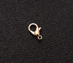 Primer plano de un cierre de mosquetón dorado pulido para joyería sobre fondo oscuro