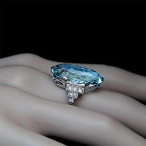 Anillo refinado de plata con un gran cristal azul óvalo y diamantes en un modelo de mano
