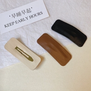Three minimalist PU leather hair clips in black, brown, and cream with pebble texture