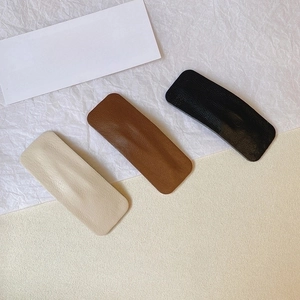 Three minimalist PU leather hair clips in cream white, caramel brown and black colors