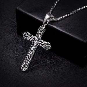 Detailed close-up of a silver crucifix pendant with religious relief on a box chain