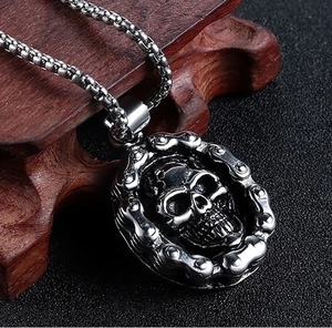 Close-up of hip hop skeleton skull pendant with vintage silver chain on dark wood
