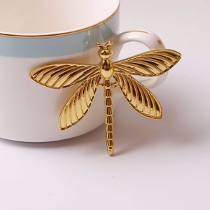 Detail of a golden dragonfly drawer handle attached to a luxury ceramic cup handle