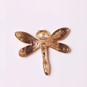 Detailed macro view of a golden dragonfly cabinet handle with a metallic polished finish