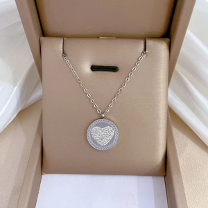 Close-up of silver heart necklace with rhinestones in a beige jewelry box on silk