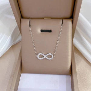 Silver infinity bow necklace with micro-diamonds in a beige luxury jewelry gift box