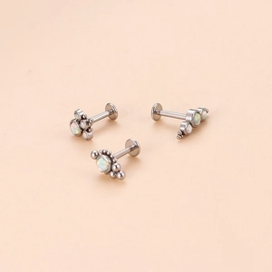 Three silver stainless steel labret studs with white opal stones on a beige background