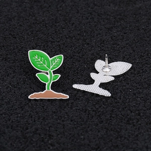 Detail view of green seedling brooches showing front enamel design and back butterfly pin clasp