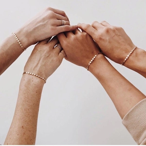 Detail of adjustable gold disc chain bracelets worn together for a layered aesthetic look