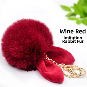 Close-up of wine red faux rex rabbit fur pompom keychain with cute bunny ears and gold clip