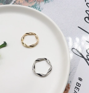 Detailed view of gold and silver irregular wavy twist rings on a ceramic plate