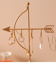 Detail view of golden arrow jewelry stand featuring five curved hooks for hanging necklaces